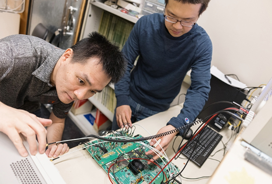 UW ECE graduate students Yi-Hsiang Huang (left) and Xichen Li (right) working on a microchip in a lab